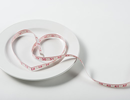   A fabric tape measure draped on an empty plate in the shape of a heart