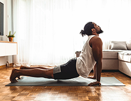 A man does yoga in his living room.