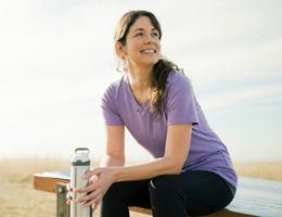 A woman holding a water bottle sits on a bench