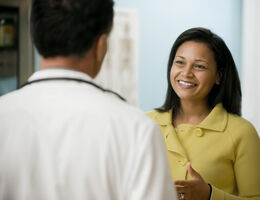 A woman smiles at a doctor