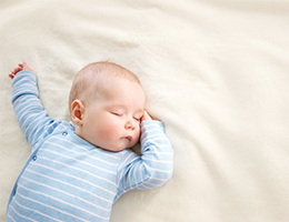 A sleeping baby in a blue onesie.