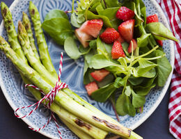 Asparagus, strawberries and spinach on a plate.