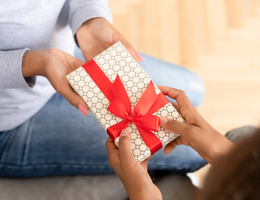 Hands giving a wrapped gift to another set of hands