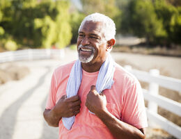 A smiling older adult outside on a sunny day.