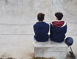 Two teenage boys sitting on a bench.